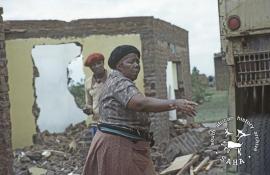 This colour photograph of a shopkeeper in her destroyed shop in Mogopa was taken by Gille de Vlieg on 12 December 1983. Included in SAHA Land Act Project report, 2014.