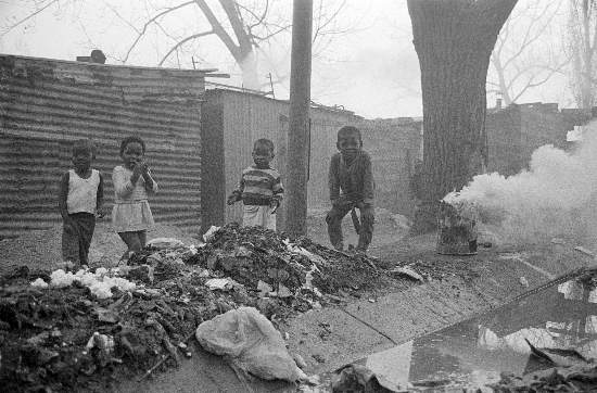 Children playing around burning rubbish in the street, Soweto, Gauteng, 14 July, 1989, Gille de Vlieg Collection, AL3274_G24.2 Children playing around burning rubbish in the street, Soweto, Gauteng, 14 July, 1989, Gille de Vlieg Collection, AL3274_G24.2