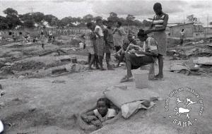 Girls relaxing in Victory Camp, with one looking out from a defence hole