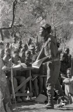 Children being taught by a soldier with a gun in JZ Moyo Camp