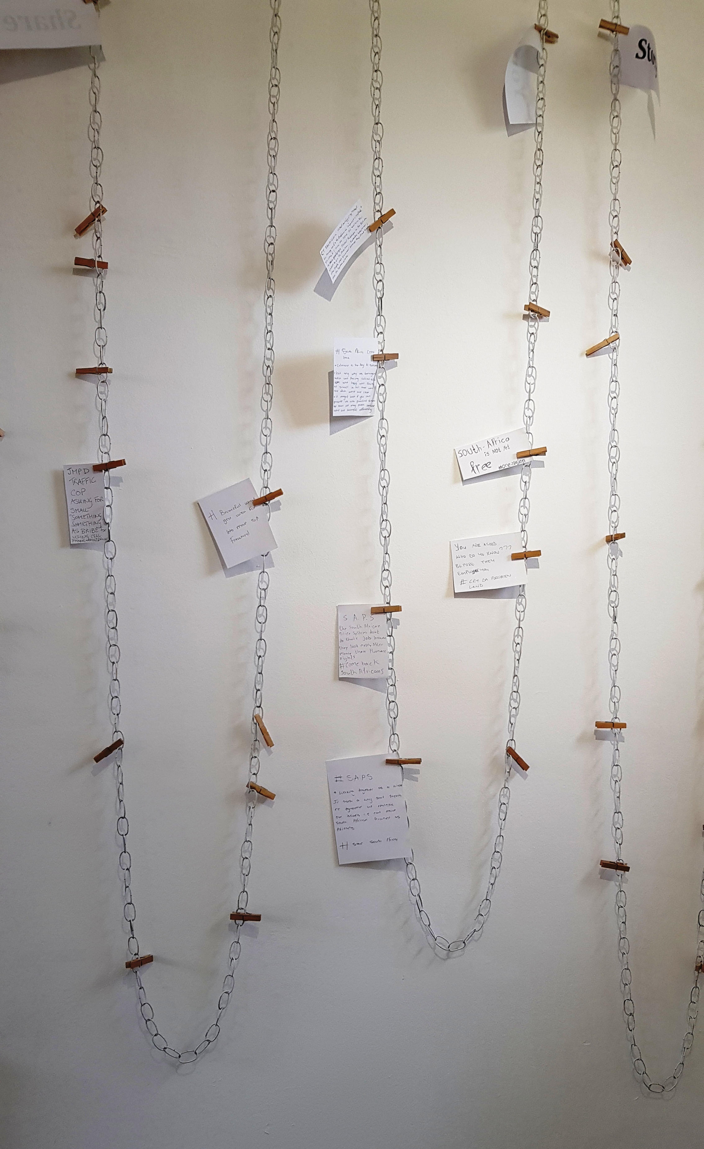 Interactive wall  with pegs holding up pieces of paper where stories are contributed